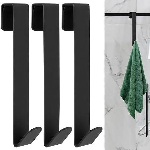Trois crochets noir mat suspendus au bord d’une porte de douche en verre