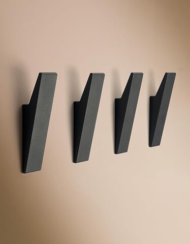 Quatre patères murales en aluminium noir mat à fixation cachée, installées sur un mur clair
