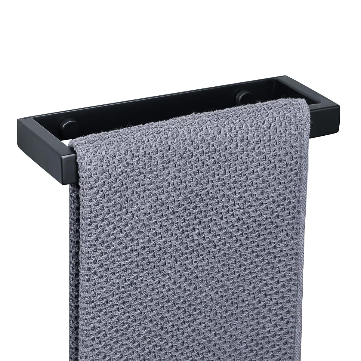 Barre porte-serviettes murale noire mate installée sur un mur minéral, avec une serviette à main claire.